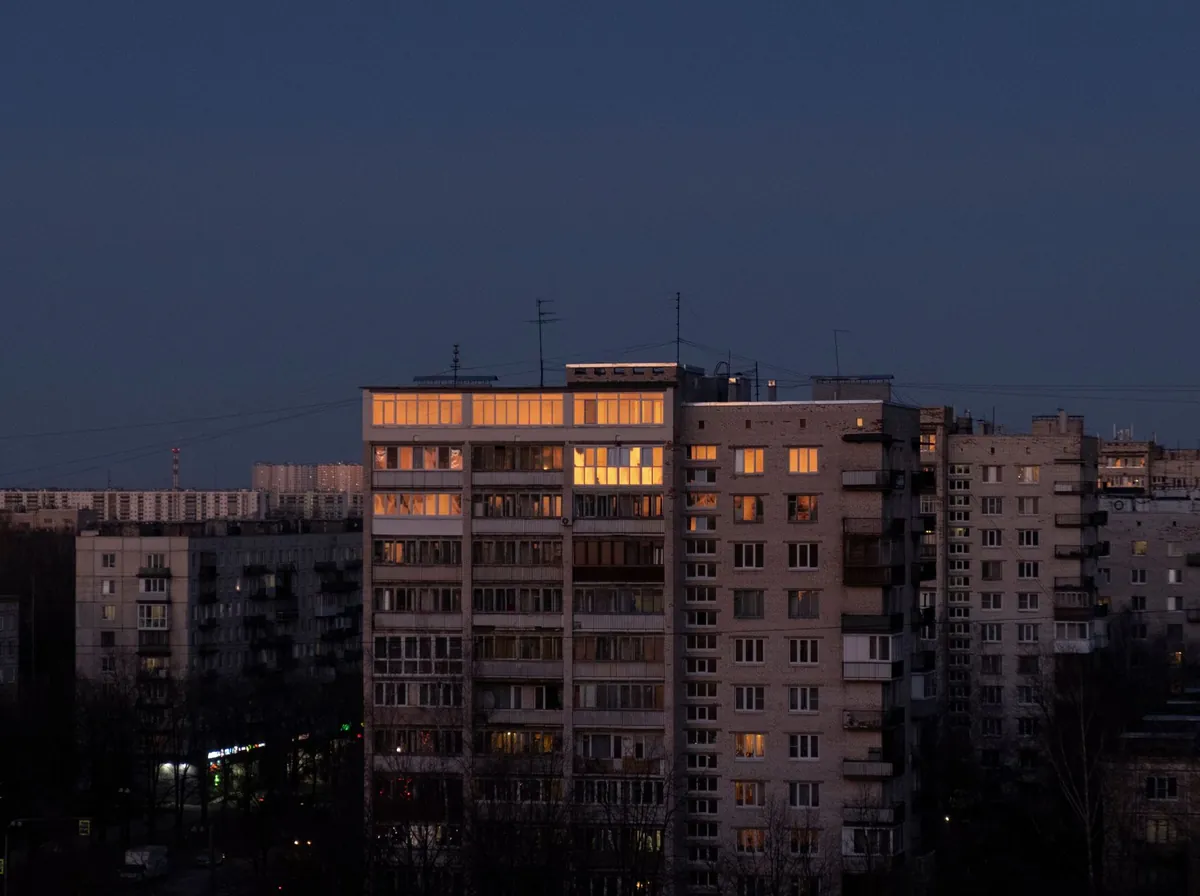 Prédios residenciais ao anoitecer, com janelas acesas