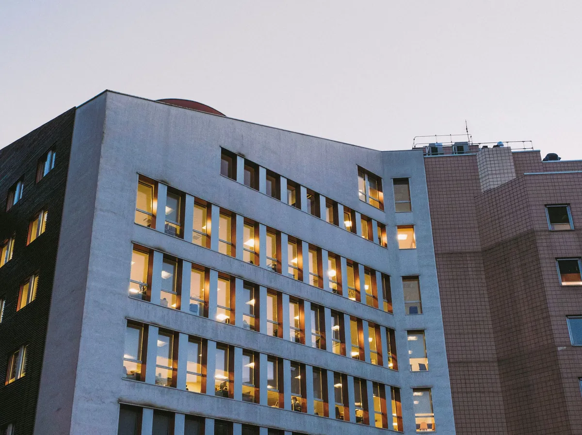 Fachada de um prédio hospitalar ao anoitecer, com janelas acesas