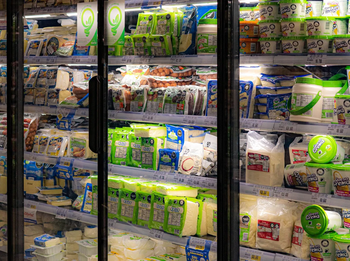 Geladeiras de supermercado iluminadas, com portas de vidro e produtos nas prateleiras